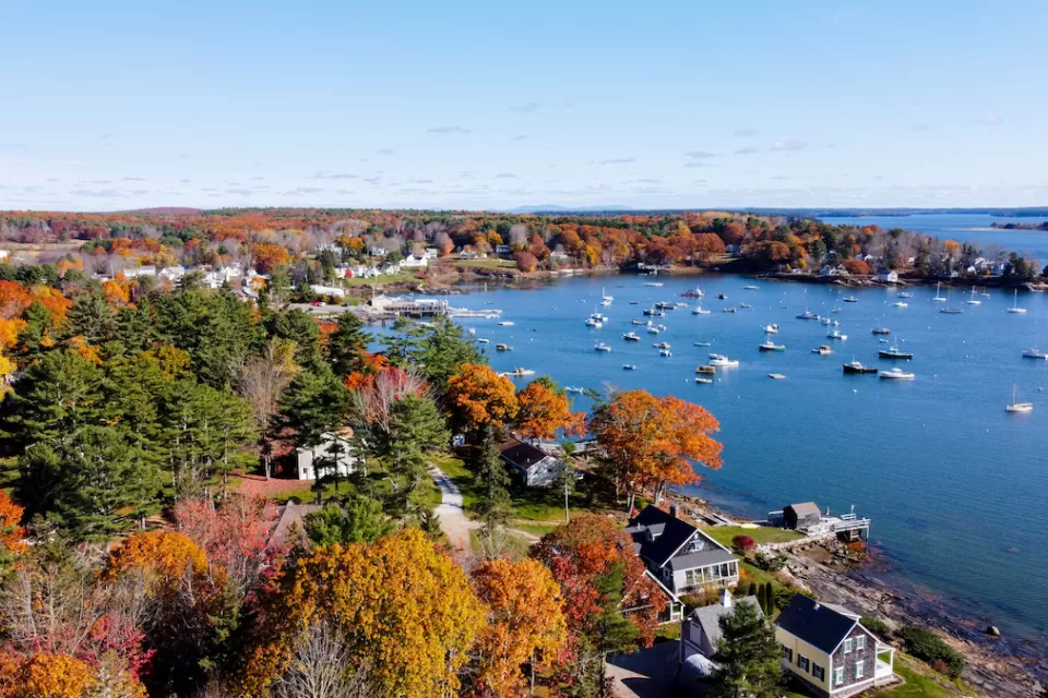 Aerial view of Maine harbor town with fall colors on trees.
